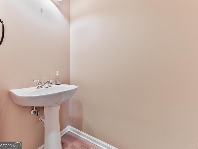 bathroom with a spacious closet, vanity, baseboards, and a bath