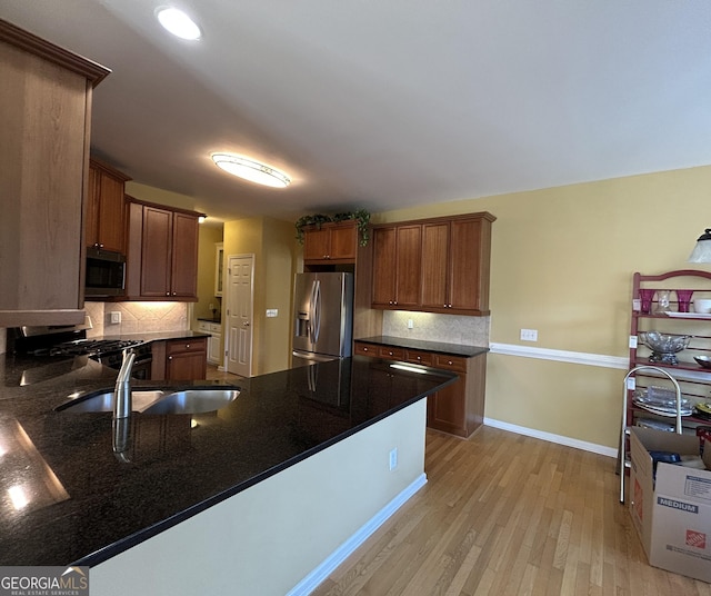 kitchen with light wood finished floors, appliances with stainless steel finishes, baseboards, and decorative backsplash