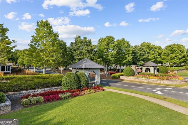 view of property's community with uncovered parking and a lawn