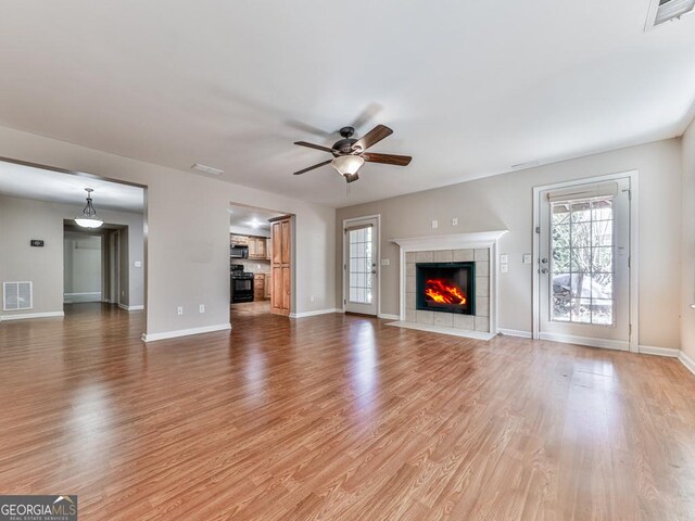 living area with a ceiling fan, wood finished floors, visible vents, and baseboards