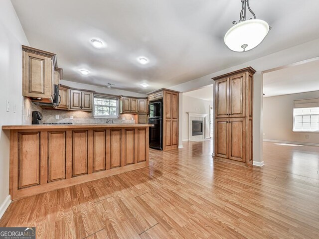 kitchen with black dishwasher, dark countertops, visible vents, a sink, and wood finished floors