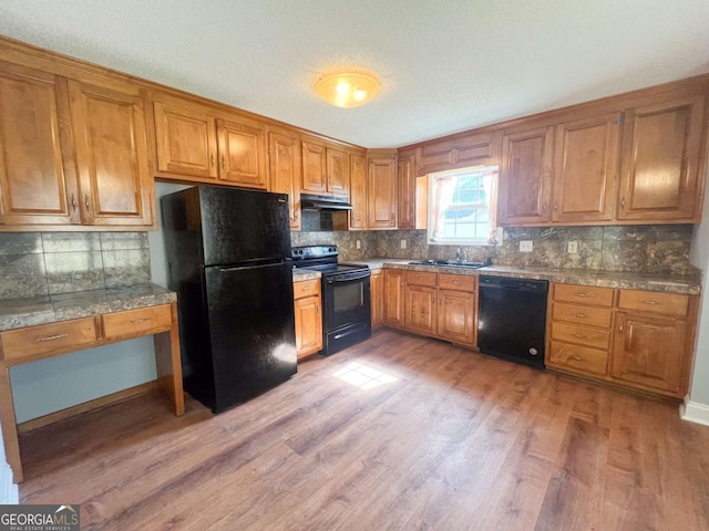 kitchen with sink, light hardwood / wood-style floors, black appliances, and decorative backsplash