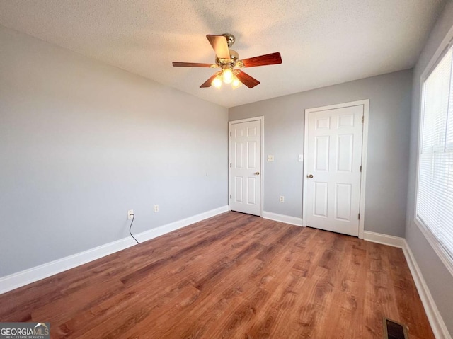 unfurnished bedroom with ceiling fan, a textured ceiling, and hardwood / wood-style floors