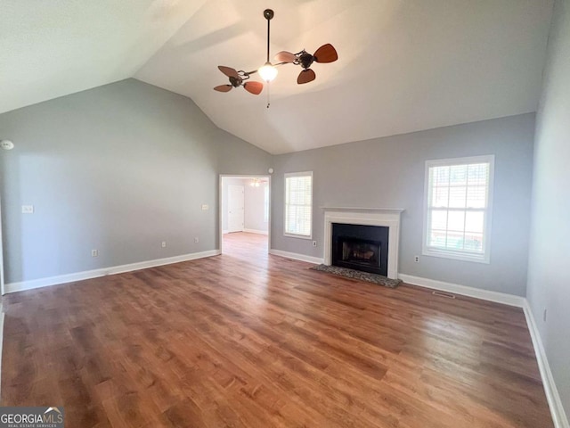 unfurnished living room featuring ceiling fan, vaulted ceiling, wood-type flooring, and a healthy amount of sunlight