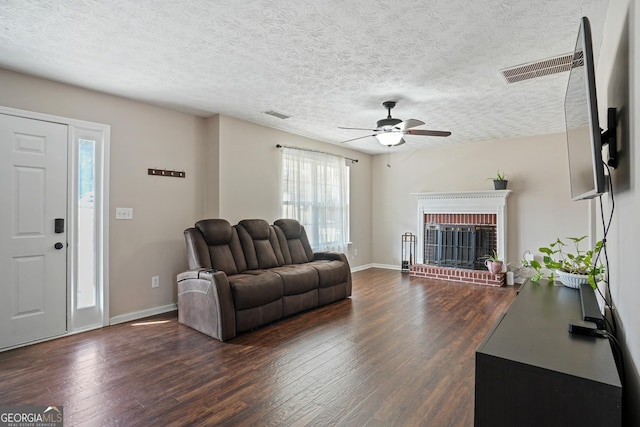 living area featuring dark wood-style flooring, a fireplace, visible vents, and baseboards