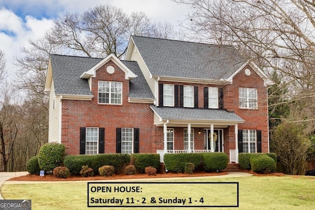 view of front of house with brick siding, a porch, roof with shingles, and a front lawn