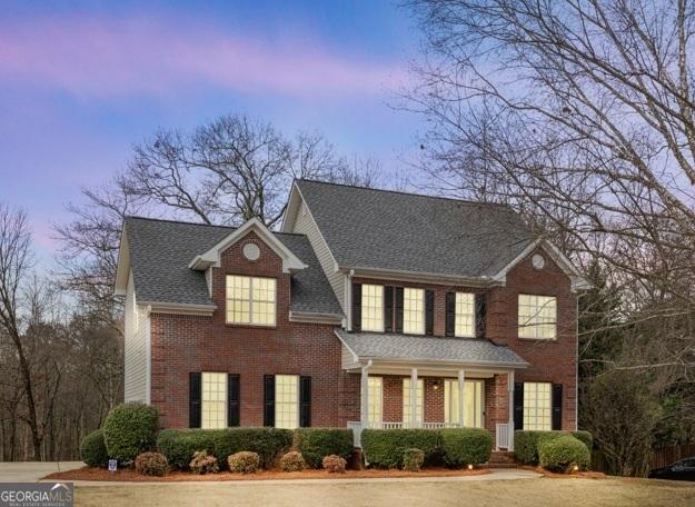 view of front of house featuring a shingled roof and brick siding