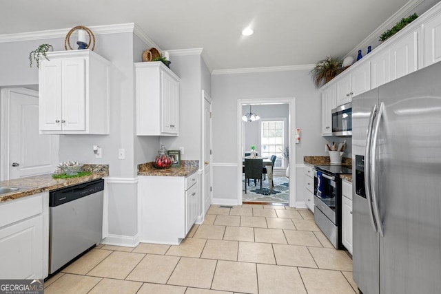 kitchen featuring dark stone countertops, light tile patterned floors, appliances with stainless steel finishes, ornamental molding, and white cabinetry