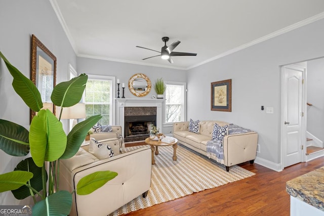 living room featuring wood finished floors, crown molding, a ceiling fan, baseboards, and stairs