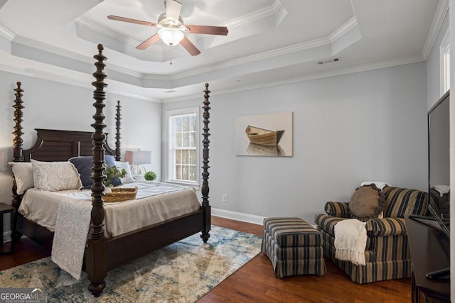 bedroom with dark wood-style flooring, a tray ceiling, crown molding, and visible vents