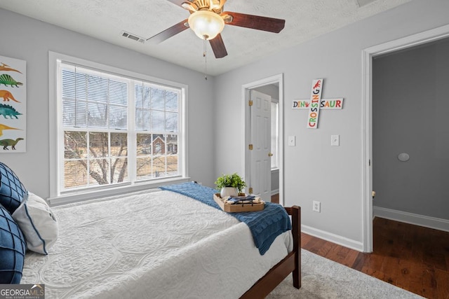 bedroom featuring visible vents, baseboards, wood finished floors, a textured ceiling, and a ceiling fan