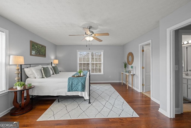 bedroom featuring dark wood finished floors, baseboards, and a textured ceiling