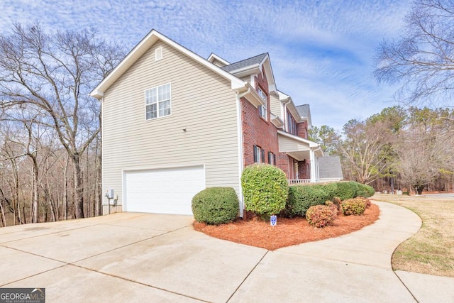 view of side of property featuring driveway, an attached garage, and brick siding