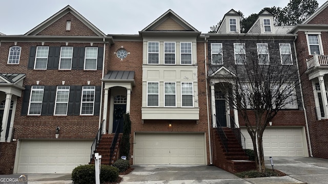 townhome / multi-family property featuring driveway, brick siding, and an attached garage