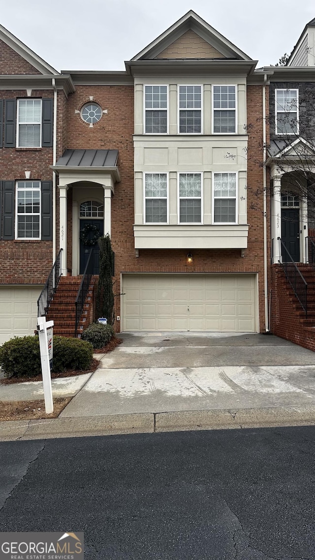 multi unit property featuring driveway, an attached garage, and brick siding