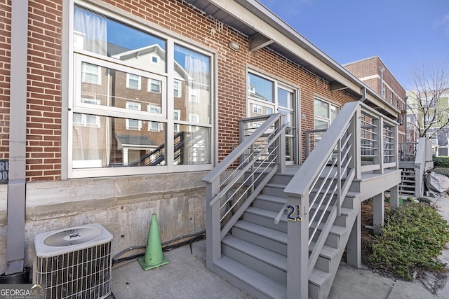 property entrance featuring central AC unit and brick siding