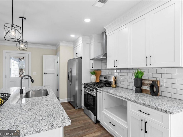 kitchen featuring sink, light stone counters, appliances with stainless steel finishes, wall chimney range hood, and pendant lighting