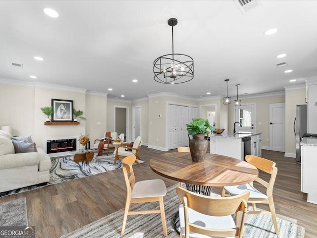 dining space with sink, crown molding, and dark hardwood / wood-style floors