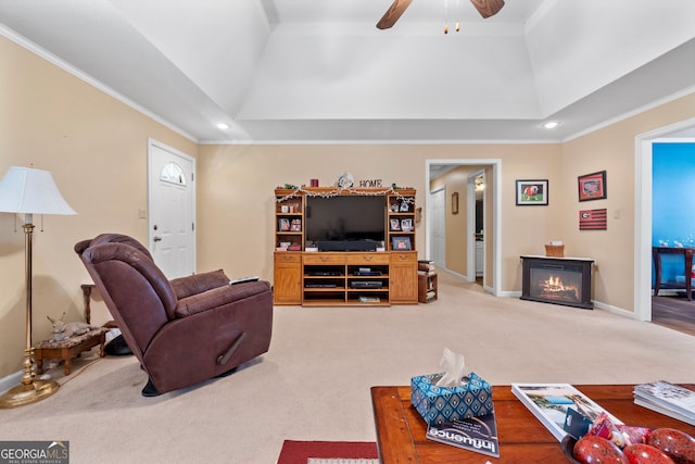 carpeted living room with a fireplace, ceiling fan, a high ceiling, and crown molding