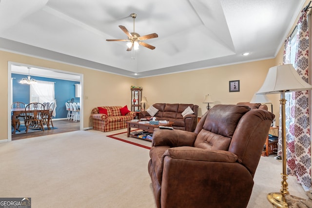 living room featuring a tray ceiling, light carpet, crown molding, and ceiling fan with notable chandelier