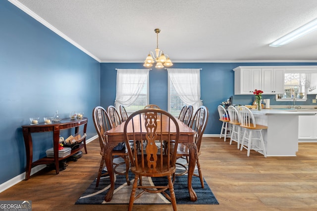 dining room with light hardwood / wood-style floors, a chandelier, sink, and a textured ceiling