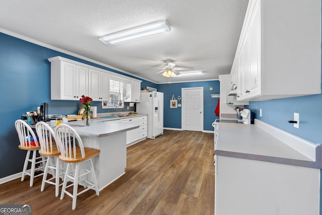 kitchen featuring white fridge with ice dispenser, a kitchen bar, and white cabinets