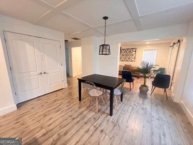 rec room featuring a barn door, coffered ceiling, and light hardwood / wood-style flooring