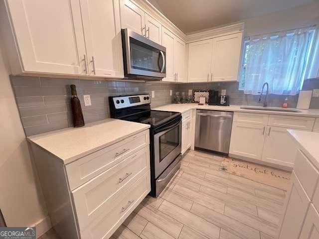 kitchen featuring white cabinets, stainless steel appliances, tasteful backsplash, and sink