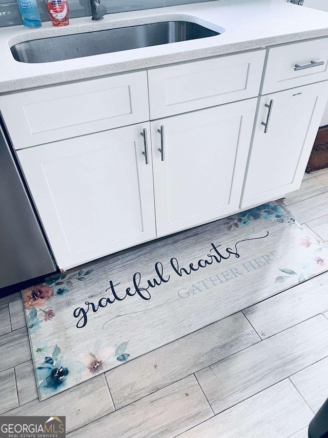 interior details with light hardwood / wood-style flooring, sink, and white cabinetry