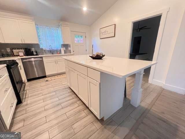 kitchen featuring black range with electric stovetop, white cabinets, stainless steel dishwasher, a kitchen island, and sink