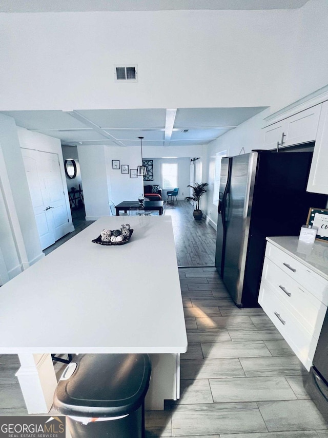 kitchen featuring a center island, a breakfast bar area, stainless steel fridge, and white cabinets