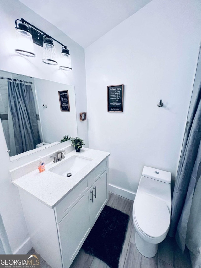 bathroom with toilet, vanity, and wood-type flooring