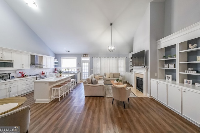 living room featuring high vaulted ceiling, dark hardwood / wood-style floors, a high end fireplace, and an inviting chandelier