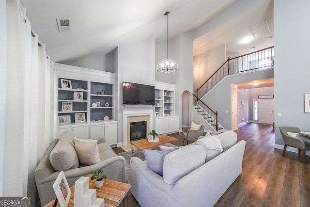 living room featuring built in shelves, a high end fireplace, high vaulted ceiling, a chandelier, and dark hardwood / wood-style flooring