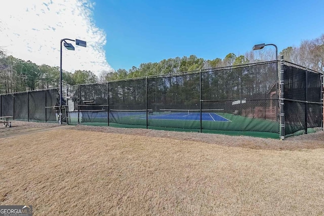 view of tennis court featuring a lawn