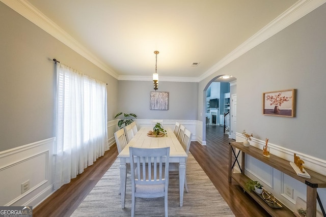 dining space featuring dark wood-type flooring and crown molding