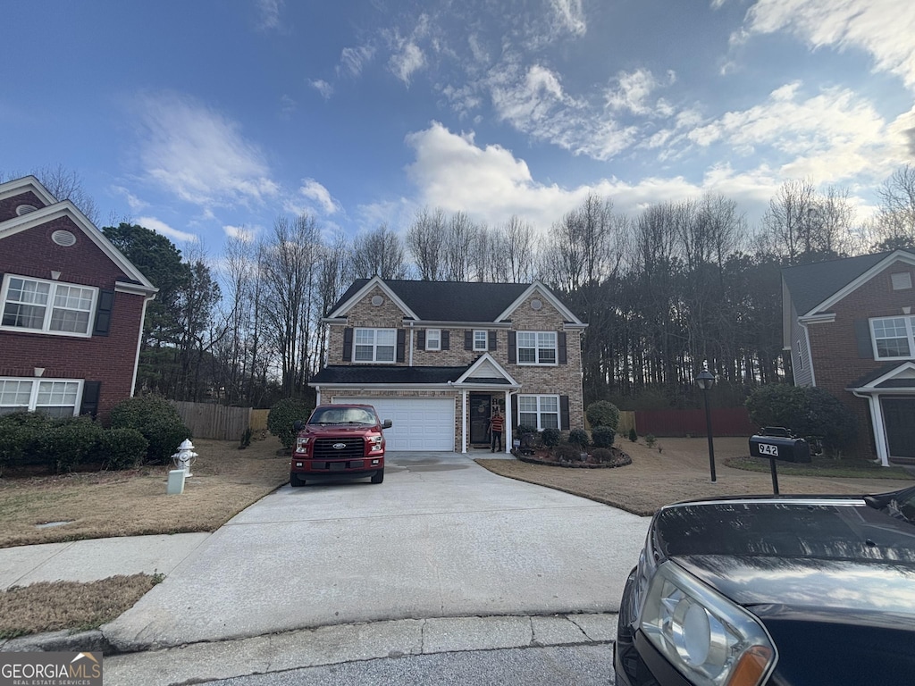 traditional-style home featuring a garage, fence, and concrete driveway