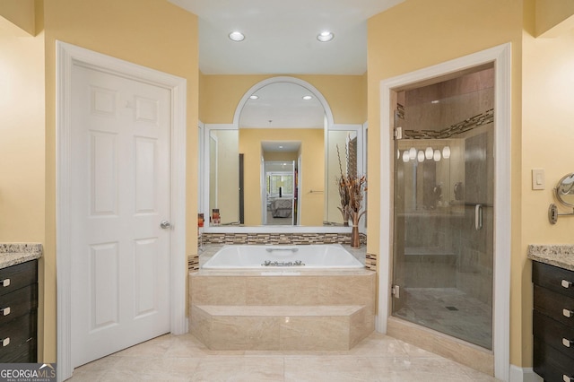 bathroom with recessed lighting, a garden tub, a stall shower, and vanity