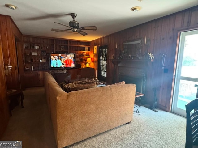 living room featuring ceiling fan, wooden walls, and carpet flooring