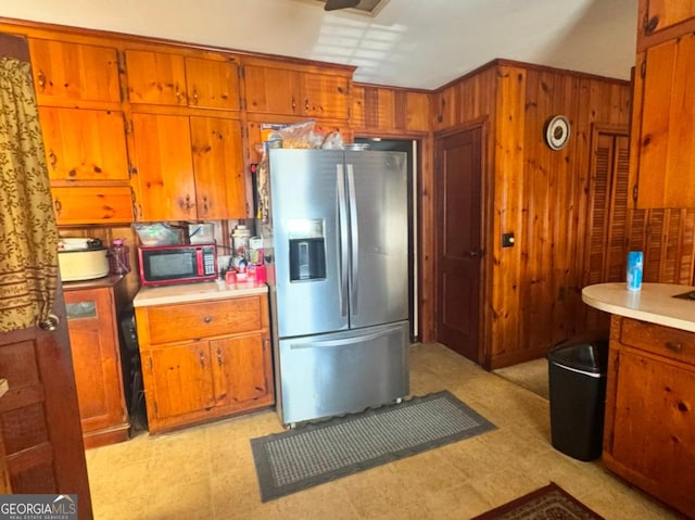 kitchen featuring ornamental molding, stainless steel fridge, and wooden walls