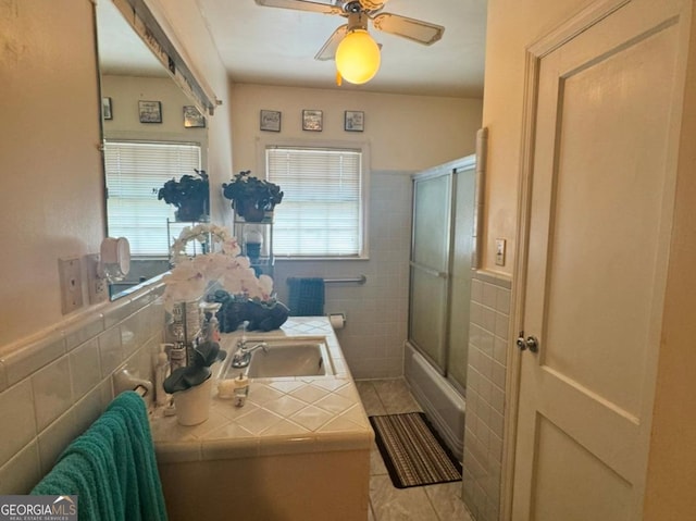 bathroom with tile patterned floors, tile walls, bath / shower combo with glass door, and a healthy amount of sunlight