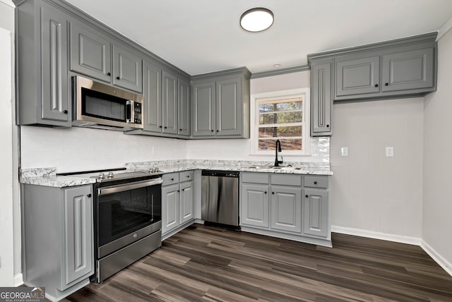 kitchen with tasteful backsplash, dark wood-style floors, stainless steel appliances, gray cabinetry, and a sink