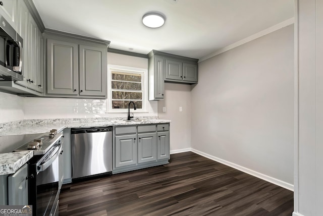 kitchen featuring appliances with stainless steel finishes, ornamental molding, a sink, and gray cabinetry