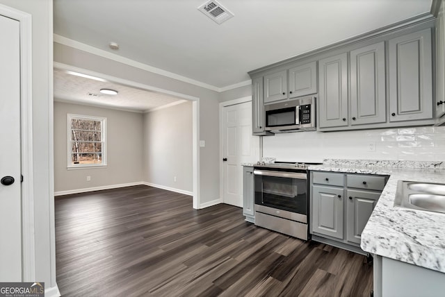 kitchen with visible vents, dark wood finished floors, appliances with stainless steel finishes, ornamental molding, and gray cabinets