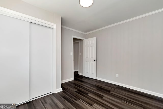 unfurnished bedroom featuring ornamental molding, a closet, dark wood finished floors, and baseboards