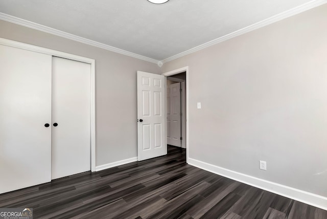 unfurnished bedroom featuring dark wood-type flooring, a closet, crown molding, and baseboards