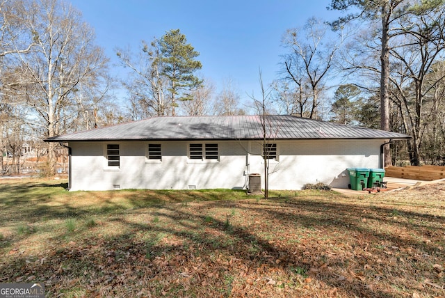 rear view of property featuring crawl space, a yard, metal roof, and brick siding