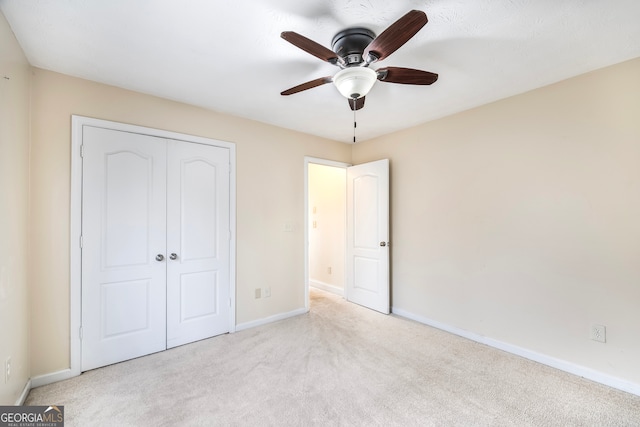 unfurnished bedroom featuring light carpet, ceiling fan, and a closet