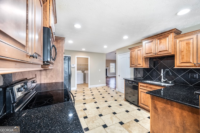 kitchen featuring tasteful backsplash, dark stone counters, black appliances, washing machine and dryer, and sink