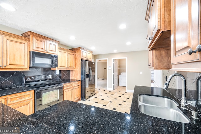 kitchen featuring sink, washer / dryer, black appliances, light brown cabinets, and tasteful backsplash